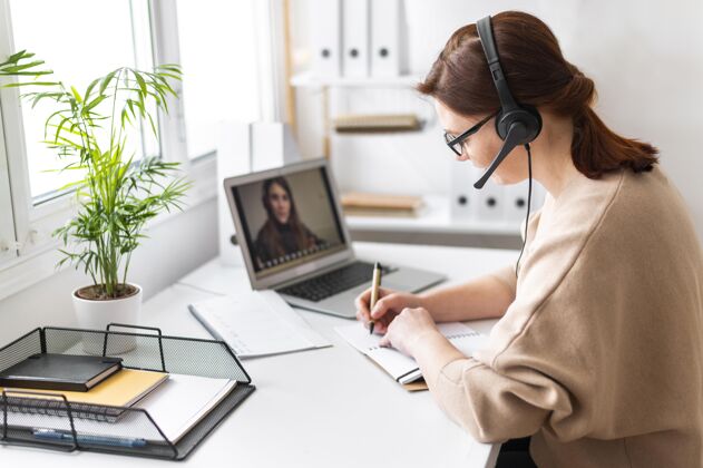 耳机工作中的肖像女性在笔记本电脑上进行视频通话模特笔记本电脑女士