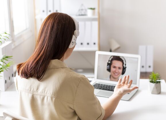 女性工作中的女人正在笔记本电脑上进行视频通话设备模型耳机