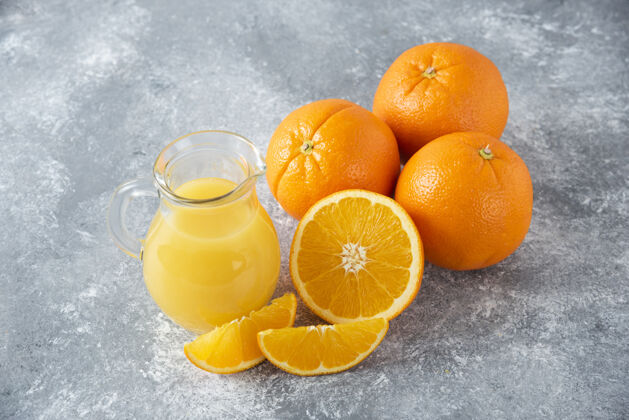 天然石桌上放着一杯果汁和新鲜的橙子果汁橙子水果