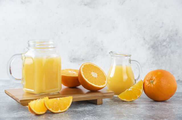 天然石桌上放着一杯果汁和新鲜的橙子水果柑橘异国情调