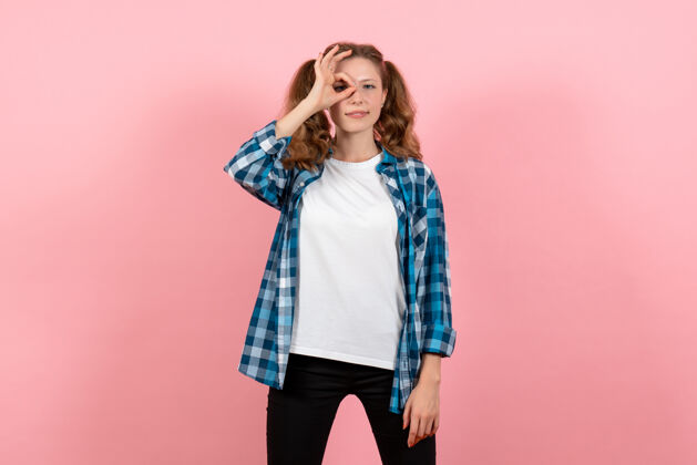人正面图穿着格子衬衫的年轻女性在浅粉色背景上摆姿势年轻女性情感模特儿颜色衬衫格子情感