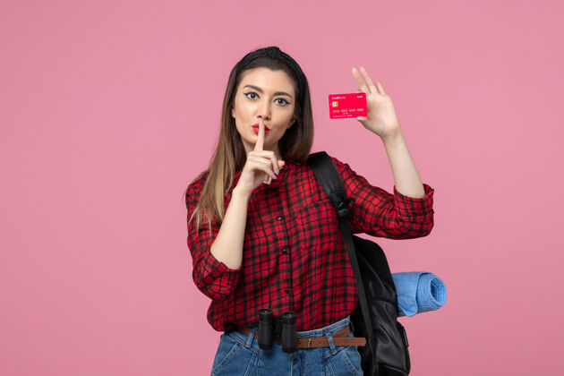 漂亮正面图身穿红色衬衫的年轻女性手持银行卡 背景为粉色人类女性颜色肖像女士持有
