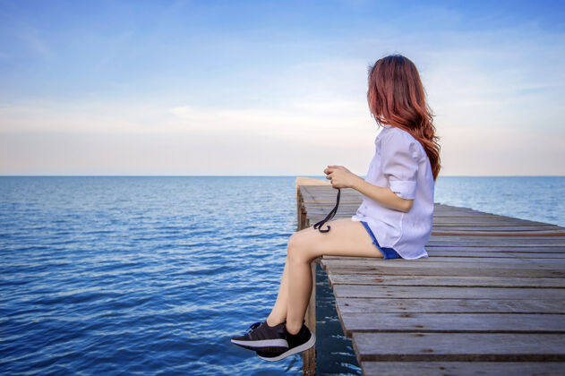 日落独自坐在海上木桥上的女孩复古风格压力情绪表情