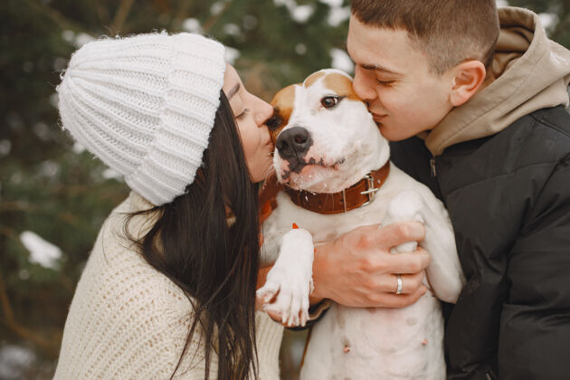 自然生活方式拍摄的夫妇在雪林与狗温暖快乐女孩