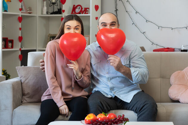 房间年轻美丽的夫妇幸福的男人和女人与心形气球微笑国际光白天