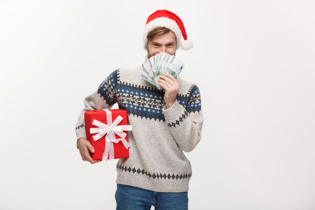 显示年轻的胡须男手里拿着圣诞礼盒和白色的钞票经济帐单快乐