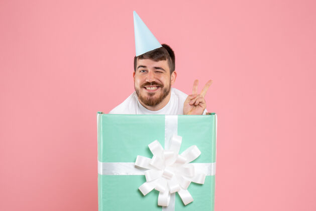 礼物正面图：年轻男性站在礼物盒内 参加粉色圣诞照片彩色情感睡衣派对年轻男性礼物里面