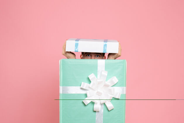 正面正面图年轻男性试图隐藏在礼物盒内的粉红色圣诞色情感睡衣派对游戏情绪试试派对