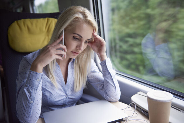 手机旅途中用手机交谈的疲惫女人笔记本电脑办公桌瘦
