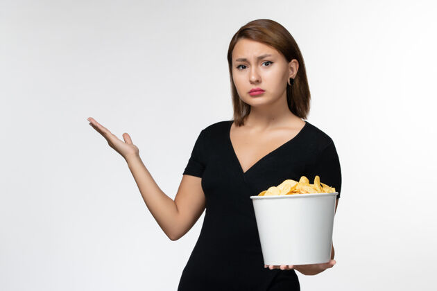 土豆正面图：年轻的女性拿着土豆片的篮子 在白色的表面上看电影剧院抱着篮子