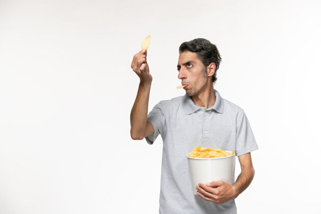 孤独正面图：年轻男性手提篮 白色表面上放着薯片电影院电影土豆