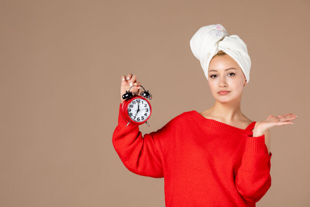 面霜正面图：年轻女性 头上戴着时钟和毛巾 背景为粉色润肤霜毛巾帽子