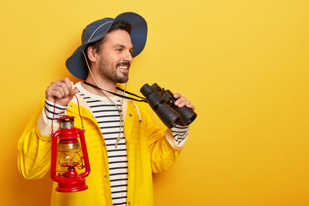 活跃快乐男旅行者有户外活动 探索世界 用望远镜和手电筒穿着防水雨衣 过着与世隔绝的黄色生活休闲姿势男人
