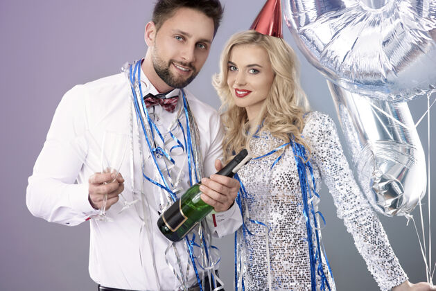 喝酒一对年轻夫妇在庆祝新年前夜气球香槟女人