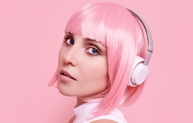 女人粉红头发的美女肖像在耳机里欣赏音乐模特快乐学生
