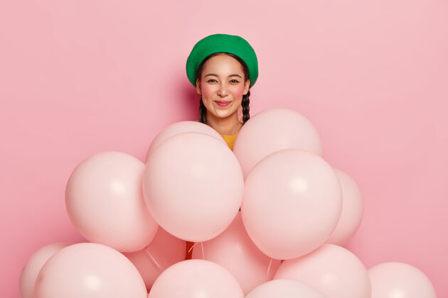 氦快乐的亚洲女人戴着绿色时尚贝雷帽 参加欢乐派对 站在氦气球后面节日喜出望外套头衫