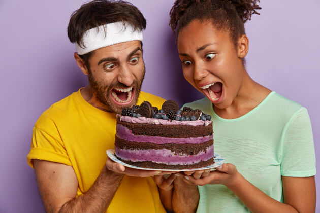 家庭夫妻俩张大嘴巴 盯着美味的蛋糕 感觉吃甜食的诱惑 穿休闲t恤选择夫妻味道