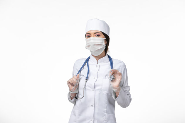 疾病正面图女医生身穿白色无菌医疗服 戴口罩 因冠状病毒-白墙上轻病毒-冠状病毒-大流行性疾病人冠状病毒防护高尔夫球手