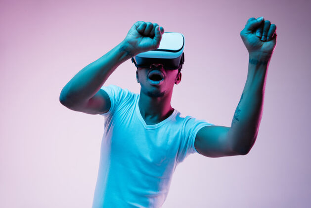 现代年轻的非洲裔美国男子的发挥和使用虚拟现实眼镜霓虹灯梯度背景明亮游戏视频
