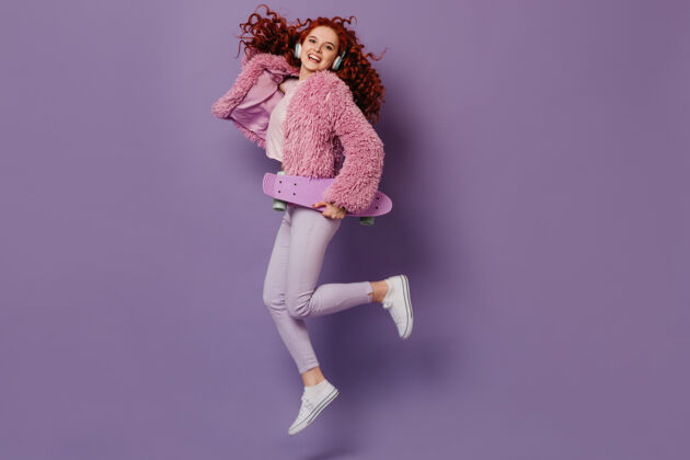 波浪发照片中是一个穿着白色牛仔裤和粉色外套的卷发女人 一个有趣的女孩跳着跳板的镜头女性别致性感