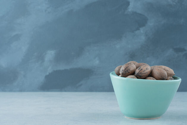 盘子在大理石背景上放满坚果的蓝色小盘高质量照片蓝色吃大理石