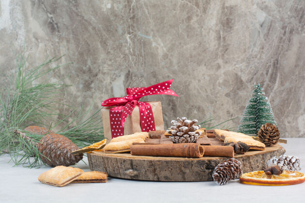圣诞树礼品盒与蝴蝶结和松果在木制板上高品质的照片礼品棍子蝴蝶结