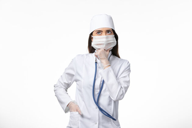 到期正面图：女医生穿着白色无菌医疗服 戴着口罩 因为柯维德-深入思考白墙疾病柯维德-大流行病毒疾病思考冠状病毒预防医生