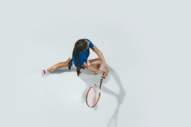 健康穿蓝色球衣打网球的年轻女子她用球拍击球室内击球与白色隔离年轻 灵活 力量和活力负空间顶视图活动活动比赛