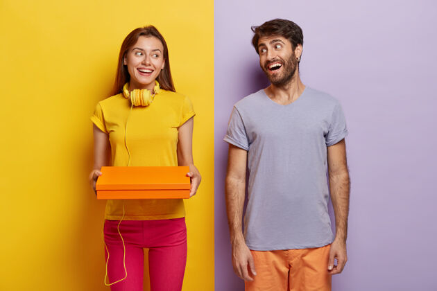 容器快乐的女人和男人在成功购物一天后满意了 拿着小盒子 穿着休闲装 站在黄紫色背景下的室内包装关系紫色