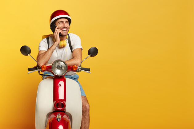 年轻人快乐英俊的男司机骑着红色头盔的摩托车坐着开车司机