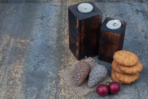节日饼干 蜡烛 闪亮的球和松果放在大理石桌上高质量的照片甜点饼干闪亮