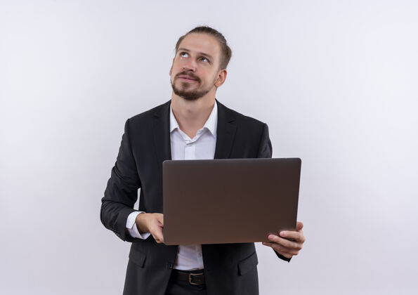西装穿着西装的帅哥拿着笔记本电脑站在白色的背景上 神情沉思地仰望着看着抱着男士