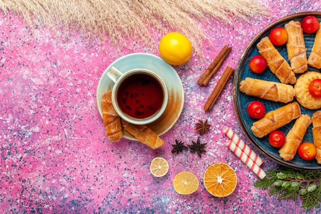 美味顶视图甜甜可口的百吉饼在托盘内与酸李子和茶淡粉红色的表面蔬菜食物生的