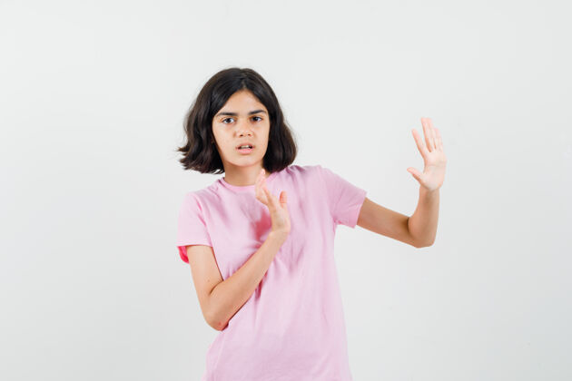 青少年小女孩手挽手保护自己在粉红色的t恤衫 看起来很害怕 前视图看美丽青年