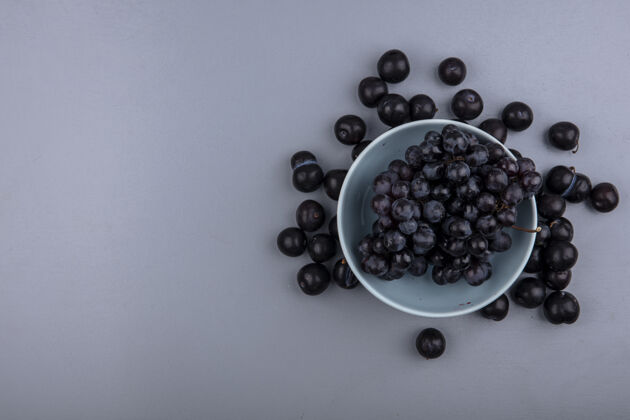 碗顶视图的水果 如葡萄在碗和树莓在灰色背景与复制空间灰色水果Sloe