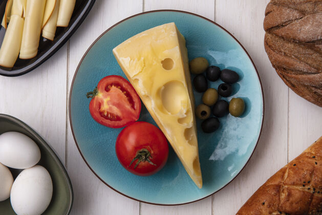 食物俯瞰玛斯丹奶酪 西红柿和橄榄放在盘子里 鸡蛋和一条黑白面包放在白色盘子里鸡蛋鸡肉奶酪