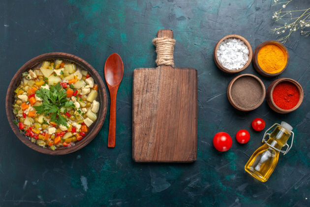 勺子俯瞰美味的蔬菜汤与油和不同的调味品对黑暗的桌子配料蔬菜汤色拉油沙拉油漆顶部