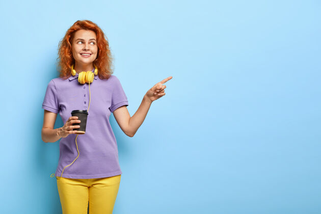促销积极的少女 红色短发 点着空闲的空间 端着一杯咖啡饮料广告青少年