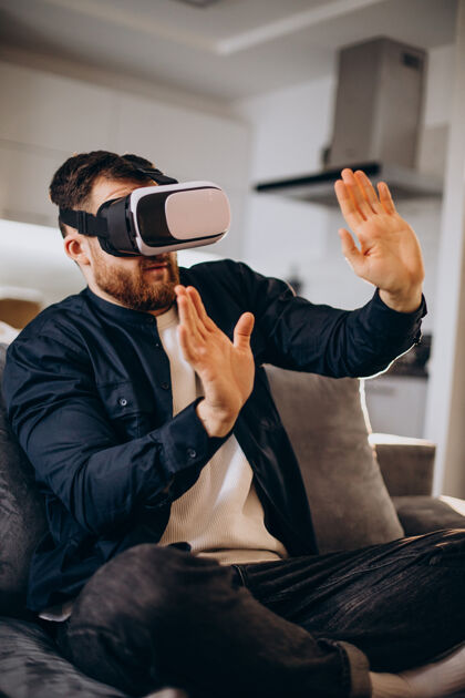 虚拟现实耳机坐在家里使用虚拟现实的男人耳机设备电影