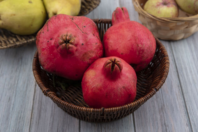 灰色一个圆形水果的俯视图 红色皮革般的果皮 石榴放在桶上 苹果和木瓜放在灰色的背景上红色视野果皮