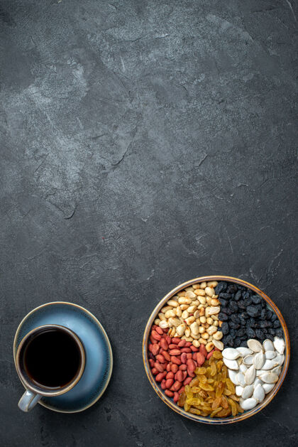 旧的顶视图不同的坚果与葡萄干和咖啡杯上深灰色背景坚果零食核桃花生不同的容器视图