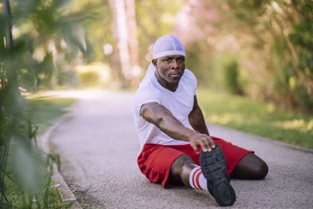 短裤一个穿着白衬衫的非洲裔美国男子在公园伸展的浅焦镜头黑健康训练