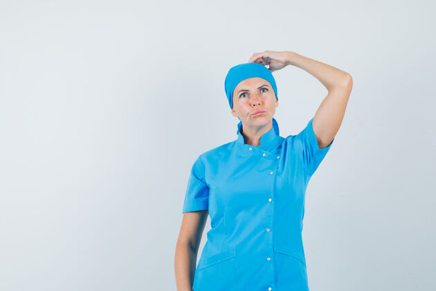 疾病身穿蓝色制服的女医生搔着头 神情沉思 前视图工作人员诊断抓伤