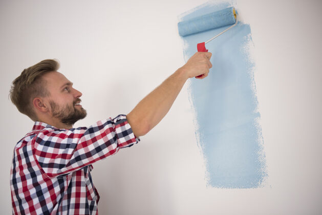 英俊年轻人在画蓝色的墙沉思期望公寓