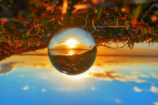云创意水晶镜头球拍摄日落时的绿色和湖泊辉光橙色魔法