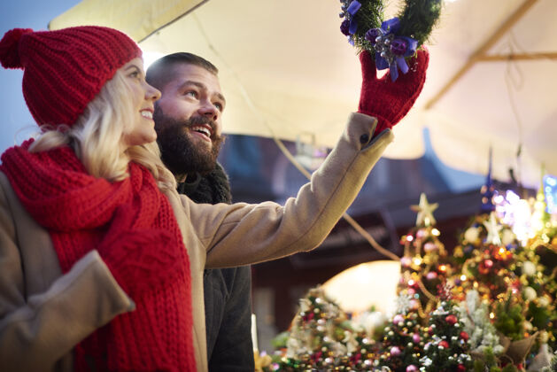 购买一对夫妇抬头看圣诞花圈城市生活街头市场圣诞饰品
