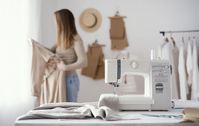 女裁缝工作室桌子上缝纫机的正视图针线活裁缝女