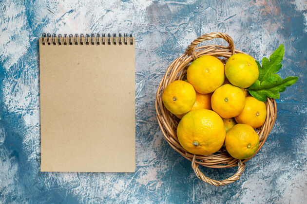 水果俯瞰柳条篮上的新鲜柑桔蓝白色表面上的笔记本笔记本多汁苹果