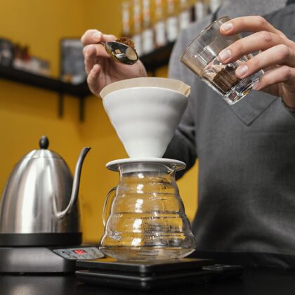 咖啡师男咖啡师把咖啡放进过滤器的低角度职业咖啡店服务员