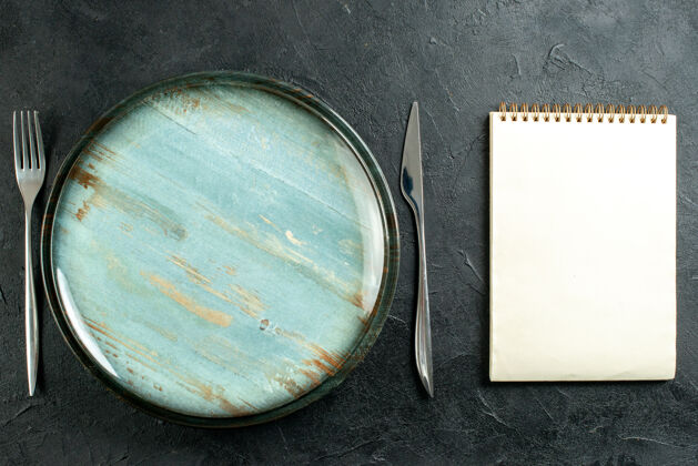 餐具俯视图圆形拼盘餐刀和叉子笔记本在黑色的桌子上叉子粉末培养皿